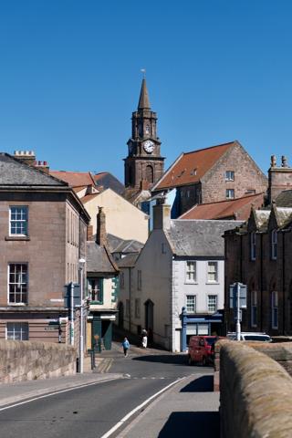 A town with buildings and a clock tower under bright sunlight.