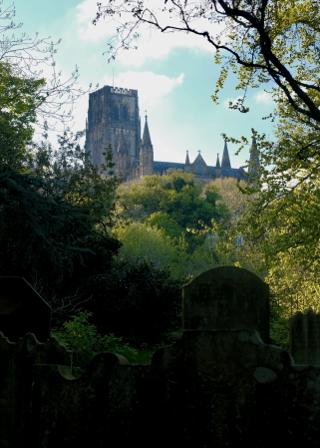 A cathedral in the distance, trees and gravestones in the foreground.