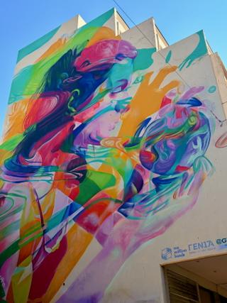 A colourful mural of a woman holding a crystal ball painted on the side of a building.
