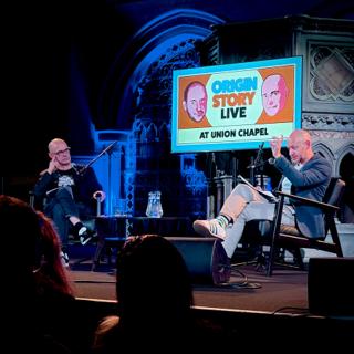 Dorian Lynskey and Ian Dunt sat on chairs behind microphones in a gothic setting.